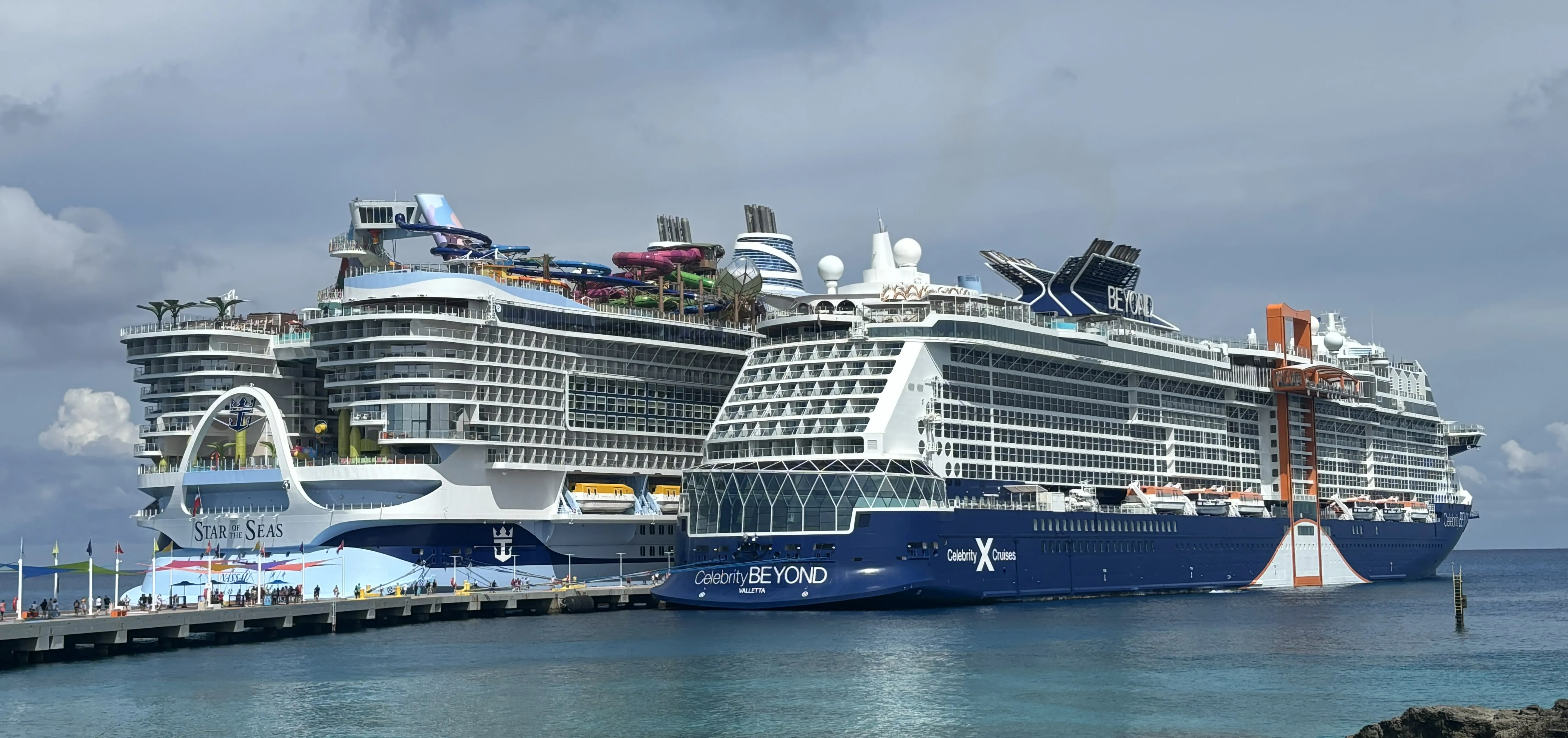 Two large cruise ships docked side by side at a Caribbean port
